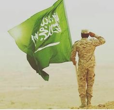 a soldier saluting the flag on top of a hill with his head in his hands