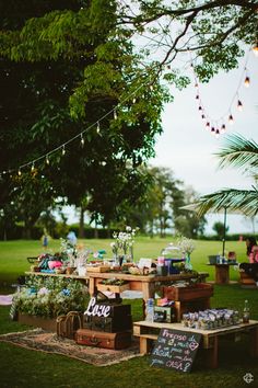 an outdoor picnic area with tables and lights strung from the trees, decorated with decorations