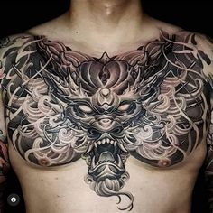 a man with tattoos on his chest is wearing a dragon head and flower tattoo design