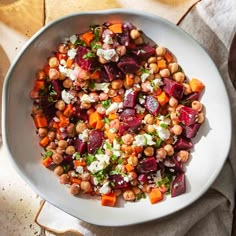 a white bowl filled with beets, carrots and feta cheese on top of a table