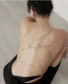 the back of a woman's shoulder with a branch tattoo on her left side