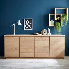 an empty room with blue walls and wooden furniture on the floor, including a sideboard