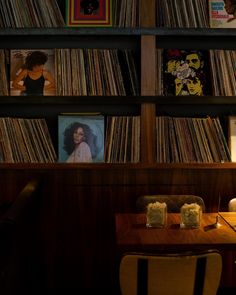 a room filled with lots of records and a wooden table topped with two chairs next to it