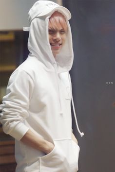 a man in a white hoodie smiles while walking