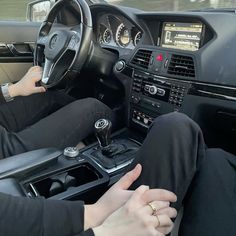 two people are sitting in the driver's seat of a car with their hands on the steering wheel