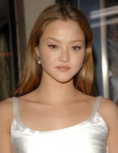 a young woman in a white dress posing for the camera with her eyes wide open