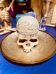 a gold plate topped with a white skull on top of a blue tablecloth covered table