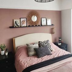 a bed room with a neatly made bed and some pictures on the wall above it