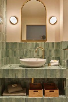 a bathroom sink sitting under a mirror next to a wooden shelf with baskets on it