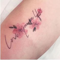 a woman's arm with flowers and the word love written in cursive writing