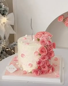 a white and pink cake with roses on it