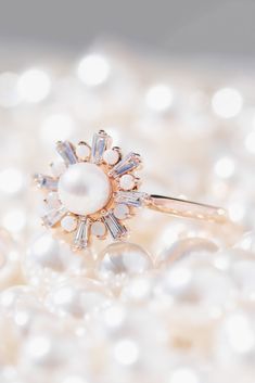 a pearl and diamond ring sitting on pearls