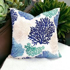 a blue and white pillow sitting on top of a chair next to a potted plant