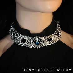 "Chunky Chain Choker with Celtic Charms, O-rings and a Blue crystal pendant. Made with tightly linked chain, 6 small O-rings going through the center of the choker and 2 triquetra celtic charms at each end of the choker.  The choker is approximately 1.5\" inches wide (3.5cm) Smallest circumference of the neck:  13\" inches (33cm) Max circumference 17\" inches (43cm) Made with a mixed alloy chain that is \"lead and nickel free\"." Gothic Round Metal Jewelry, Medieval Style Round Metal Jewelry, Gothic Blue Metal Jewelry, Blue Gothic Metal Jewelry, Medieval Round Metal Jewelry, Gothic Sterling Silver Choker Jewelry, Adjustable Blue Unique Choker, Blue Metal Choker Necklace, Adjustable Blue Choker