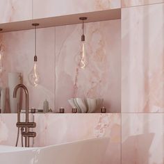 a bathroom with pink marble walls and lights hanging from the ceiling, along with a white bathtub