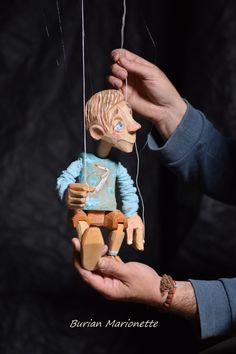 a person holding a small wooden toy in their left hand and string attached to it