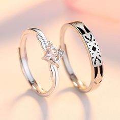 two silver rings with black and white designs on the sides, one has a flower