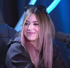 a woman with pink hair and sunglasses sitting down