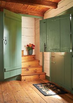 a room with wooden floors and green cupboards on either side of the door, next to a stair case