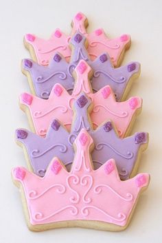 decorated cookies with pink and purple frosting are arranged in the shape of princess crowns