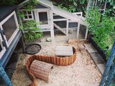 a small chicken coop in the middle of a yard with plants growing around it and an outdoor seating area