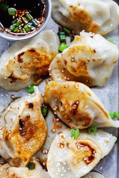 dumplings with sesame seeds and green onions on a tray