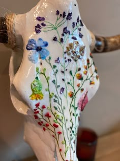 a cow skull with flowers painted on it's side and antlers in the back