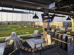 an indoor golf course is seen through the glass walls in this modern office building, with couches and televisions