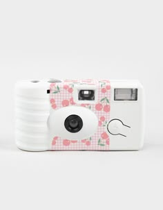 a white camera sitting on top of a table next to a pink and white checkered background