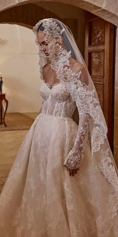 a woman in a wedding dress with long sleeves and veil on her head is posing for the camera