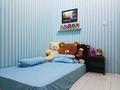 two teddy bears sitting on top of a bed in a room with blue striped walls