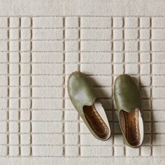 a pair of green shoes sitting on top of a white floor next to a rug