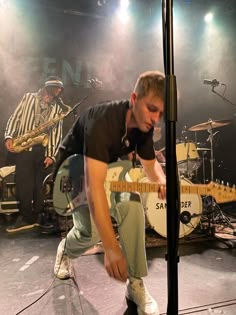 a man playing guitar on stage with other musicians