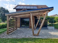 a wooden structure with a solar panel on the roof and windows in front of it