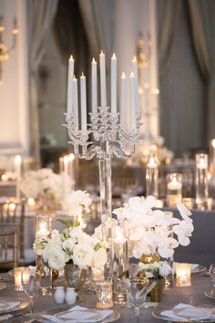 the centerpieces on this table are all white flowers and candles in glass vases