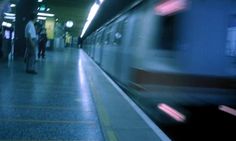 two people are walking on the platform near a subway train at night, with motion blurry in the foreground