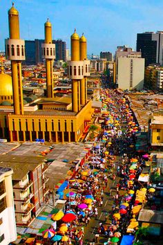 an aerial view of a city street with many people and umbrellas in the foreground