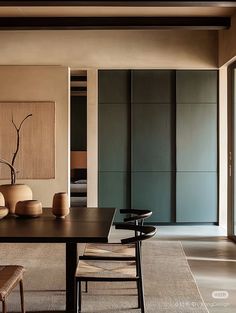 a dining room table with chairs and vases on it in front of sliding glass doors