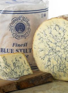 a piece of cheese sitting on top of a cutting board next to a bag of blue stuff