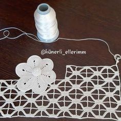 a white piece of yarn sitting on top of a table next to a spool of thread