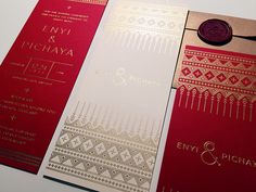 three red and gold wedding cards on top of each other