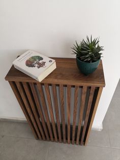 a book is sitting on top of a wooden shelf next to a potted plant