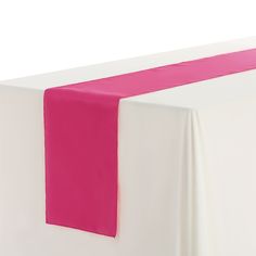 a pink and white table runner on top of a bed