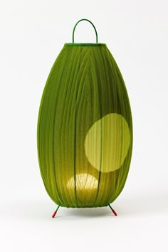 a green vase with two circles in the center and a red stand underneath it on a white background