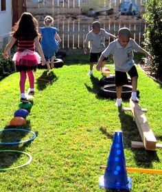 several children playing in the yard with plastic cones and tees on the grass,