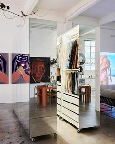 a mirrored closet with clothes hanging on it's sides and paintings in the background