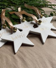 three white ceramic stars with gold lettering on them