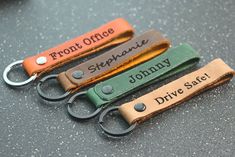 three personalized leather keychains with name tags on them, sitting on a table