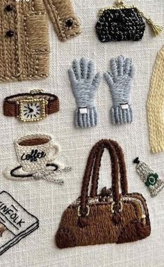 several different types of handbags and purses on a white tablecloth with embroidered details