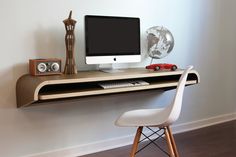 a computer monitor sitting on top of a desk next to a white chair and clock